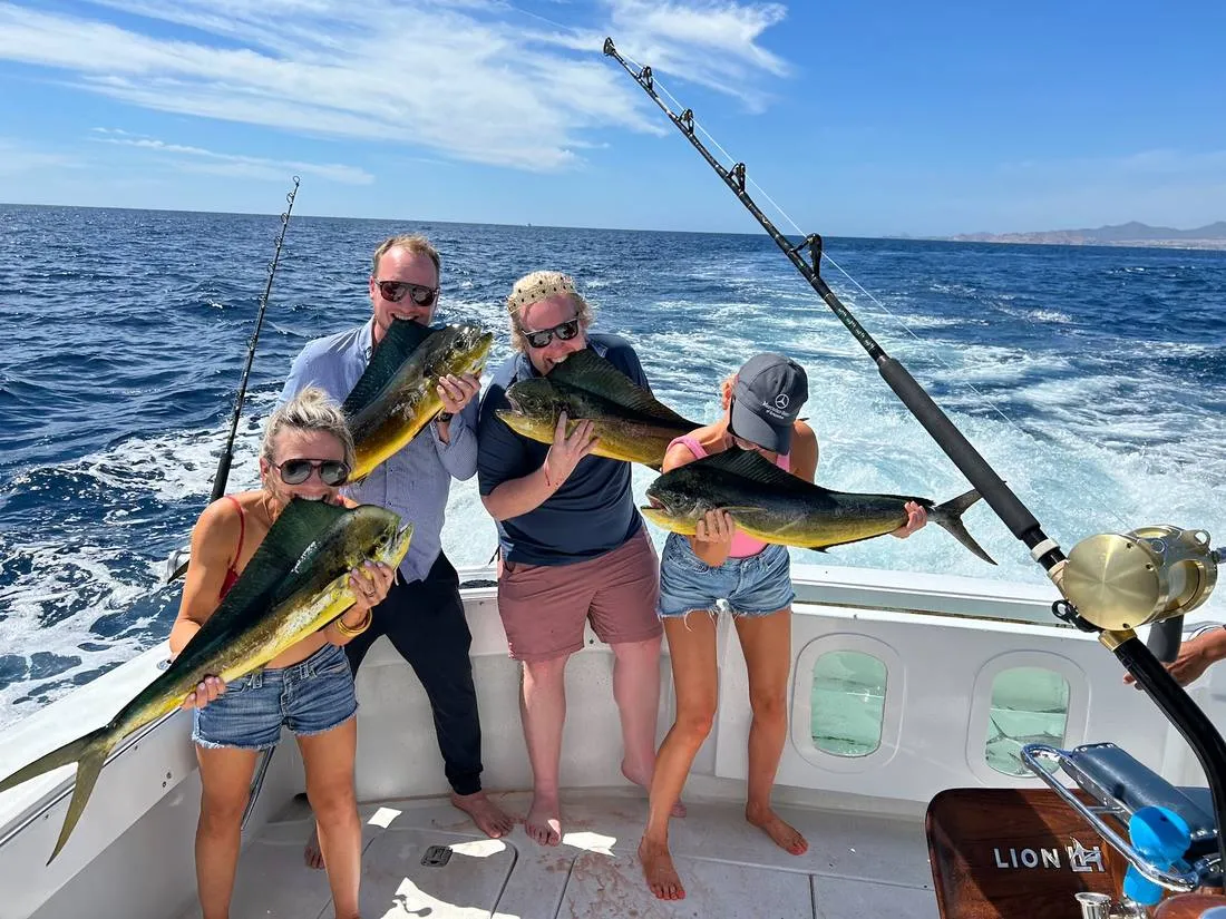 Guests biting mahi-mahi catch aboard Lion Heart sport fishing charter Cabo San Lucas
