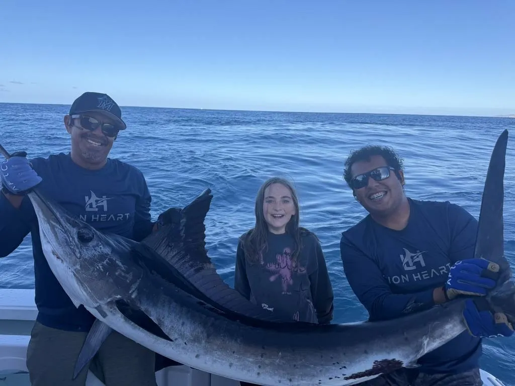 Lion Heart crew and young girl with trophy striped marlin offshore Cabo San Lucas